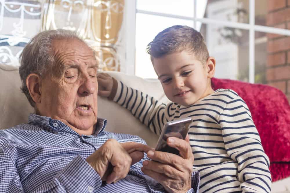 a grandfather receiving home care for the elderly in his own home having fun with his grandson